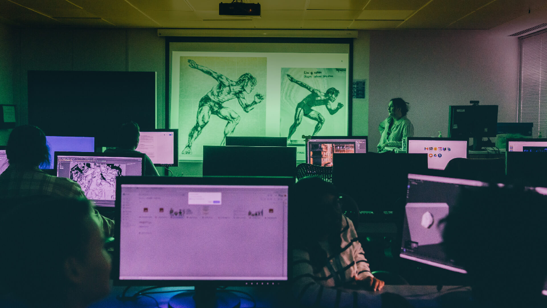Studio classroom with students working on computers and a tutor at the front