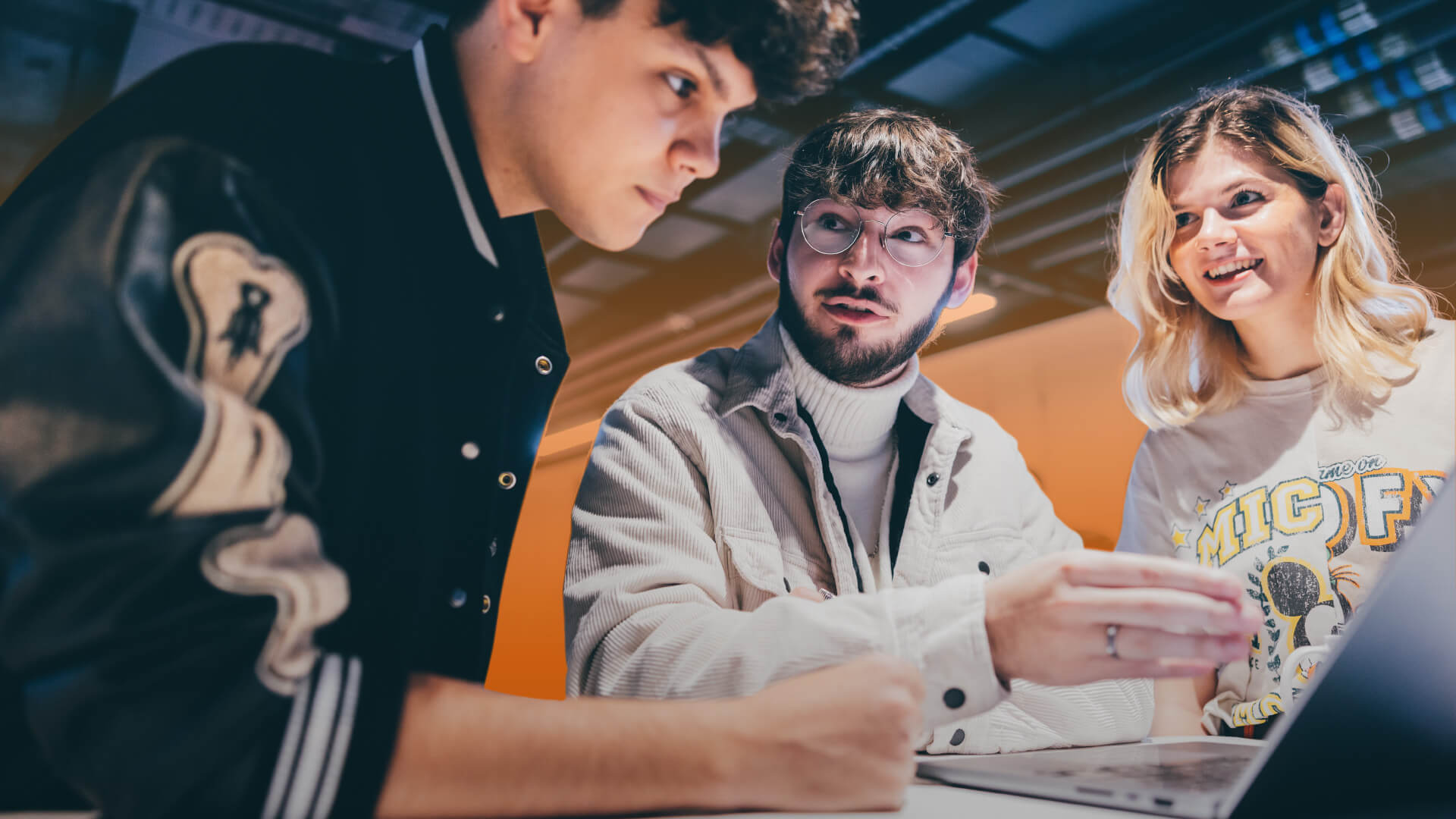 Three students looking at a laptop screen